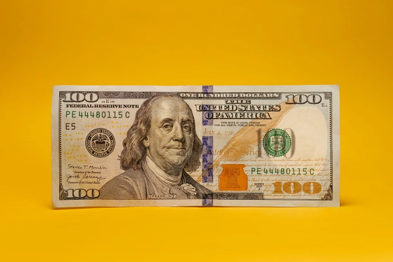 a hundred dollar bill with a yellow background