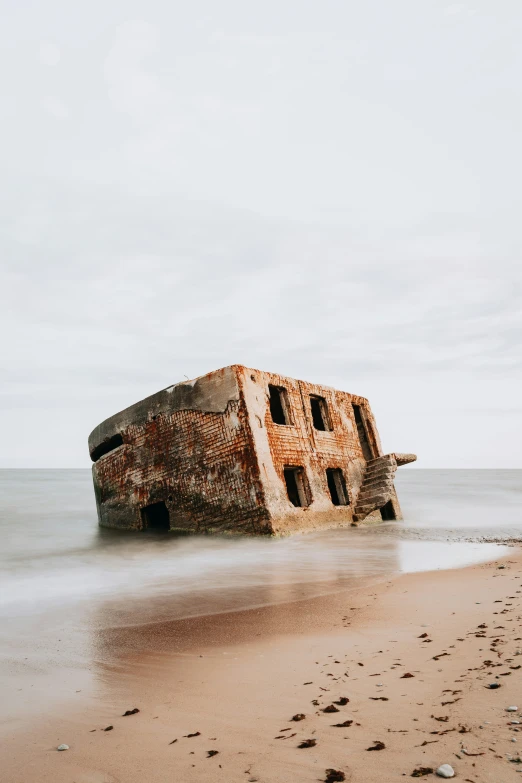 a very old building is on the sand near the water