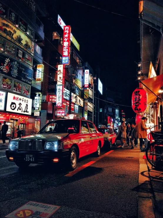 the city street has neon signs and parked cars