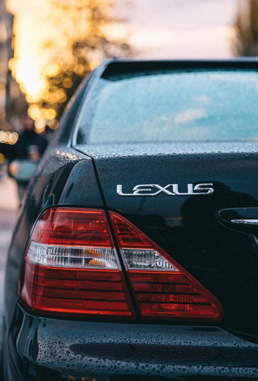 the back end of a black car on a city street