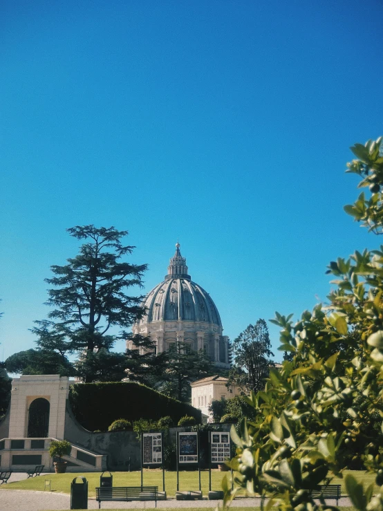 a domed structure stands between some trees and shrubbery