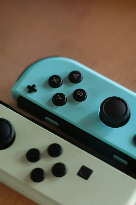 two video game controllers sit together with black ons