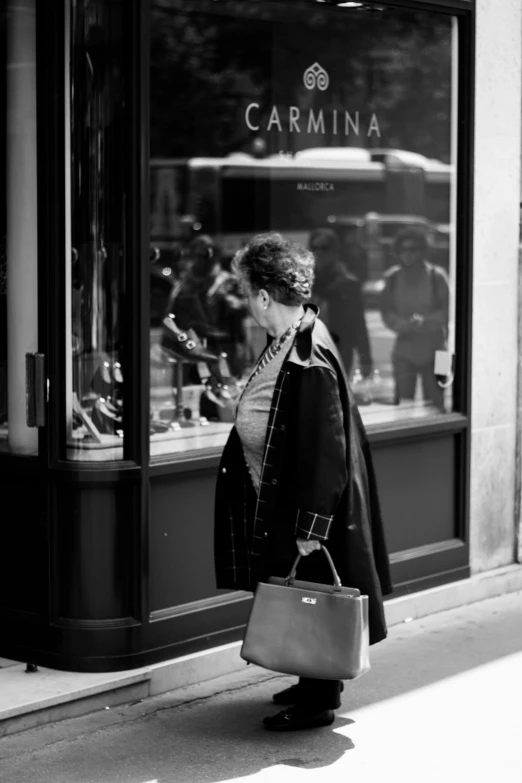 a lady walks by a store window holding a purse