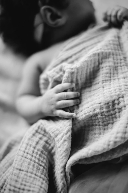 a newborn baby wrapped in a blanket on the bed