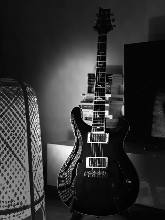 a black guitar sitting next to a tall book shelf