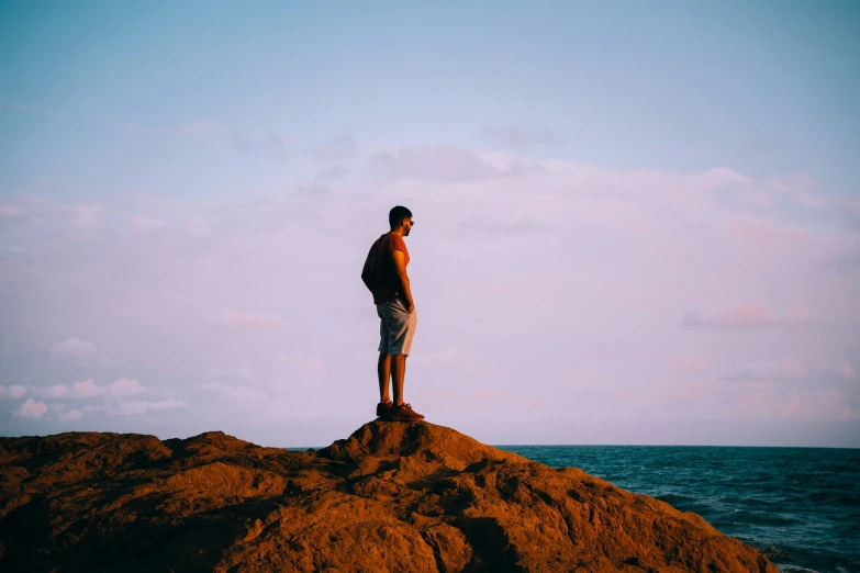 a person stands on the edge of an island in the middle of the ocean