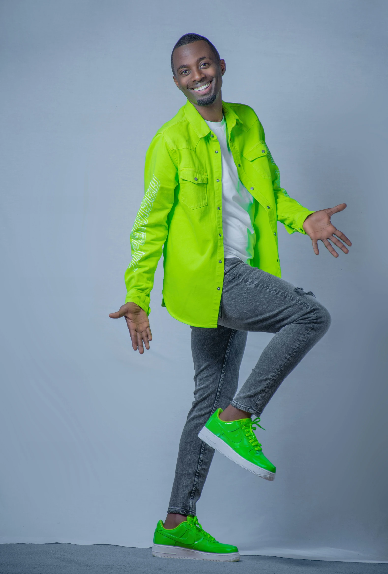 an african man posing while holding onto green sneakers