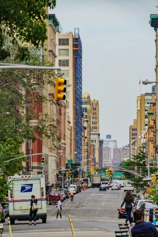 city street with cars and people with cars, trucks, busses and buildings