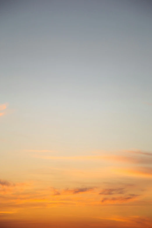 a lone airplane flying in the sky during sunset