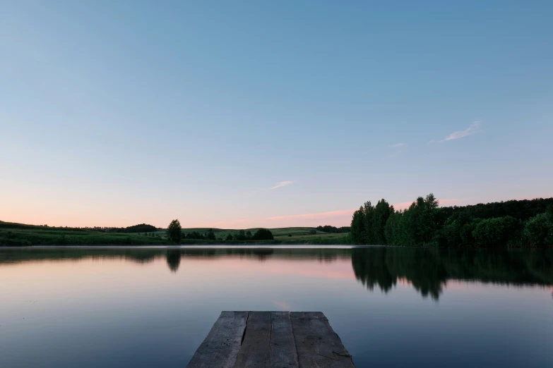 an empty dock is on a calm lake