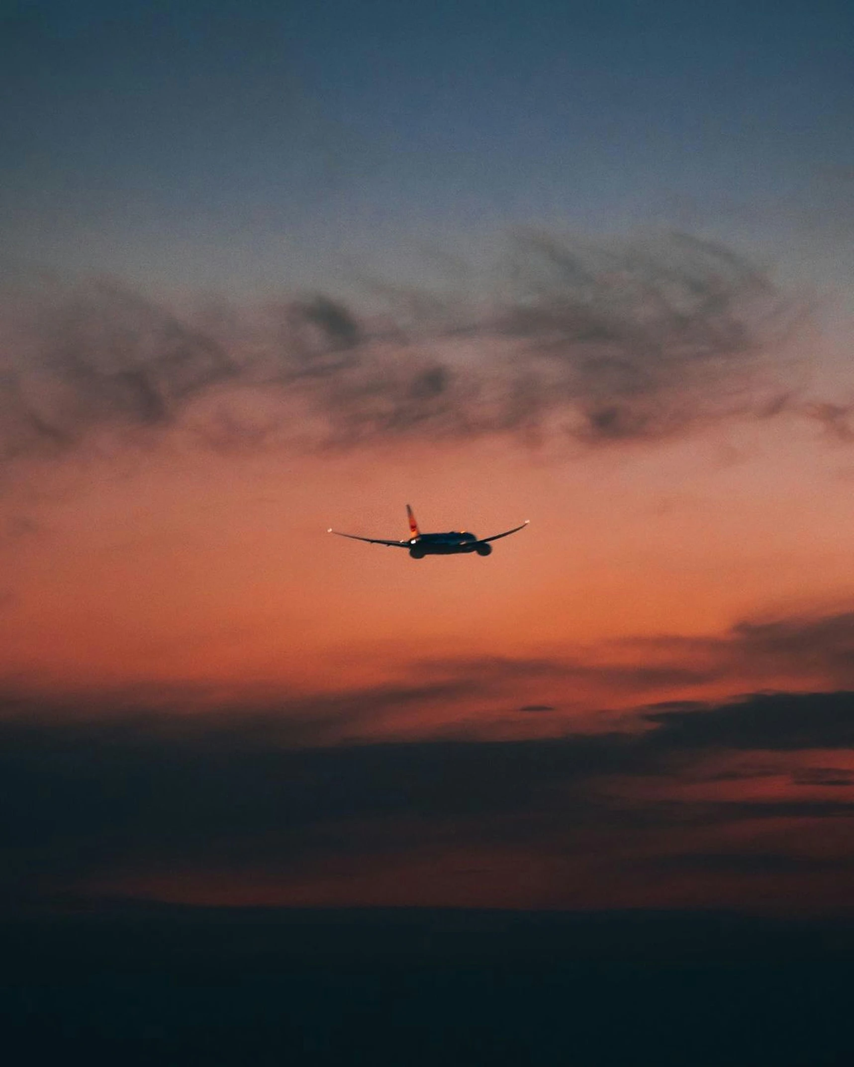 a plane flying in the distance during a sunset