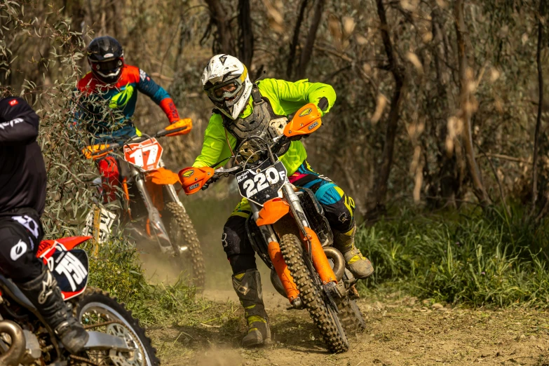 two dirt bike riders race through the woods