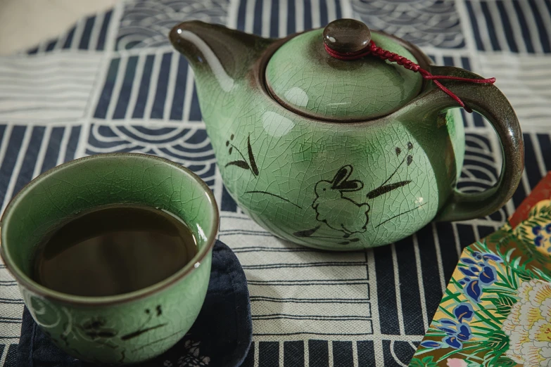 a green tea pot and cup with chinese writing on it