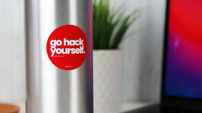 a red sticker that says go hock yourself is next to a computer
