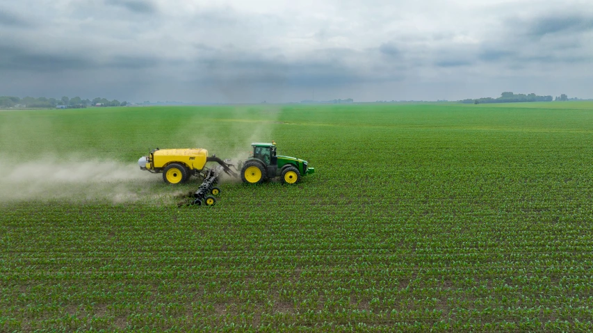 tractor being sprayed by sprayer on open field