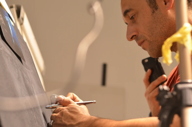 a man working on his painting using a screwdriver