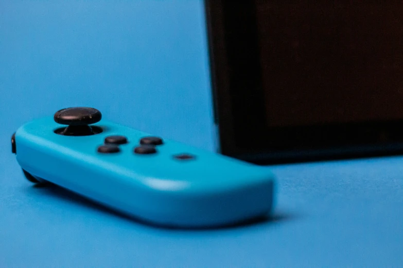 a nintendo wii controller is laying on the blue surface