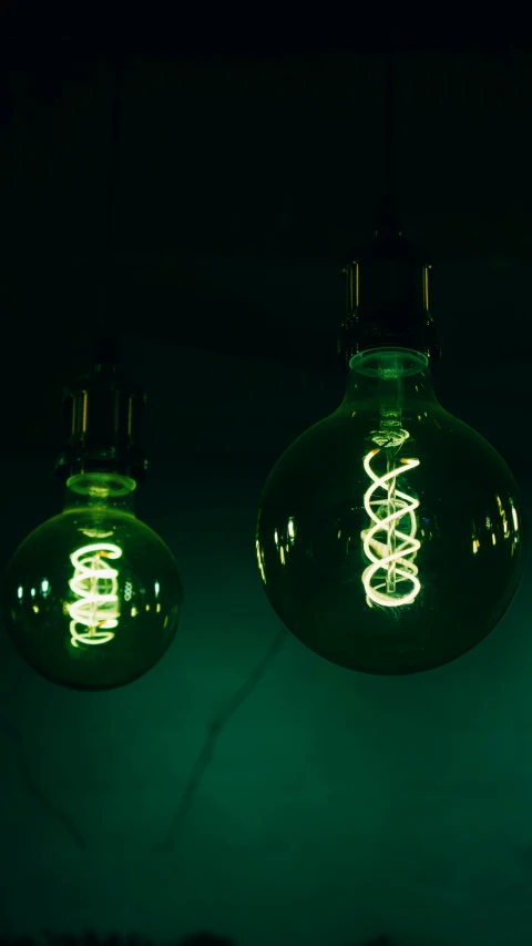 two green light bulbs hanging off of the ceiling