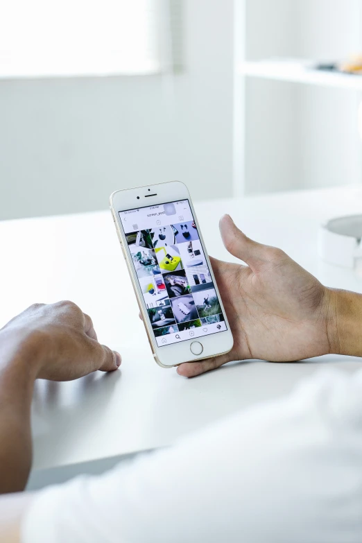 a woman holding up an iphone at her desk