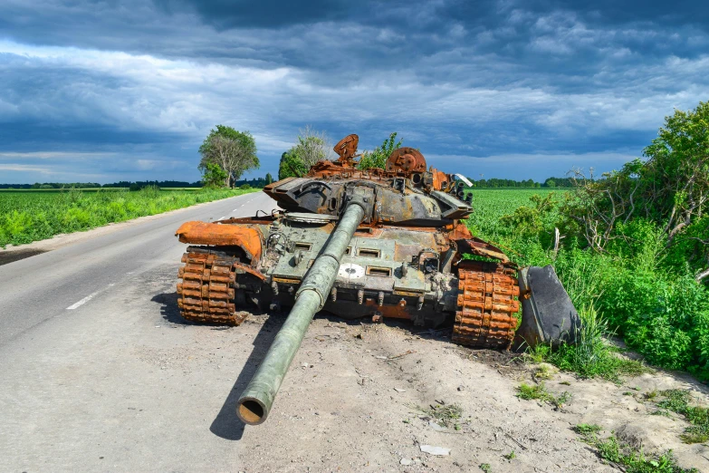 a rusty tank laying on its side beside a road