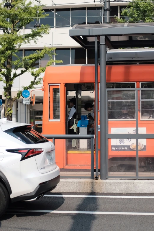 an orange train at a train station waiting to cross the street