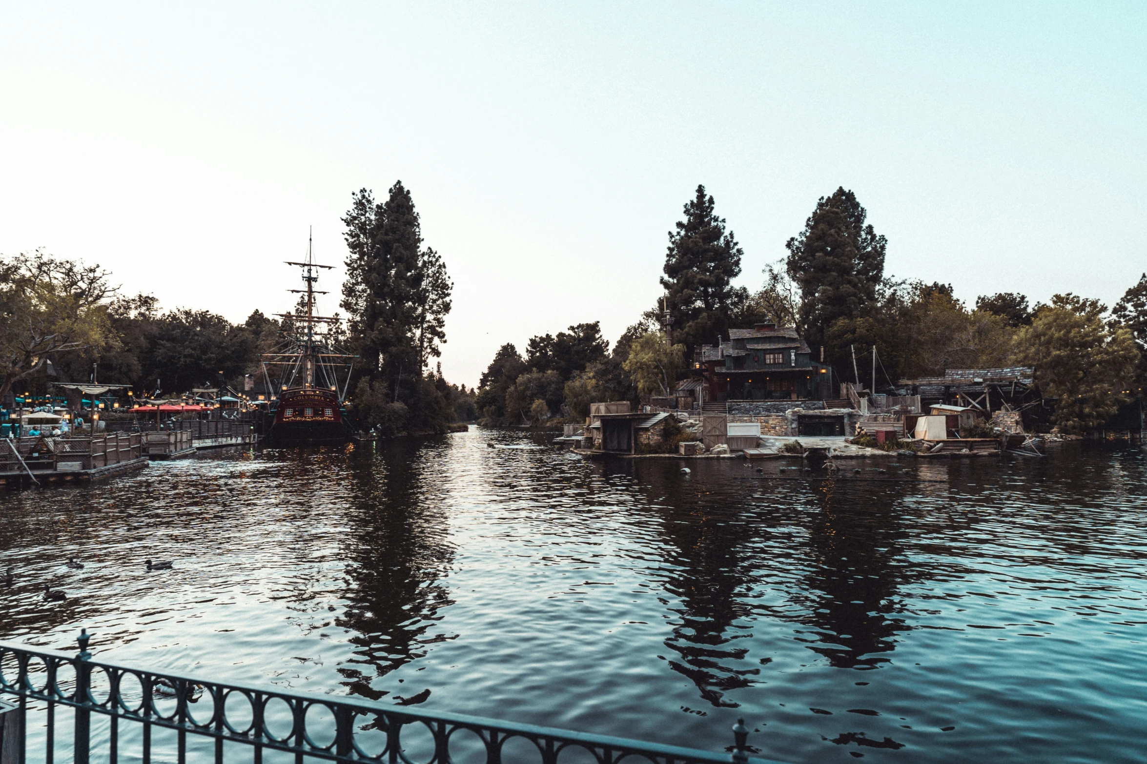 boats parked on the river next to trees and bridge