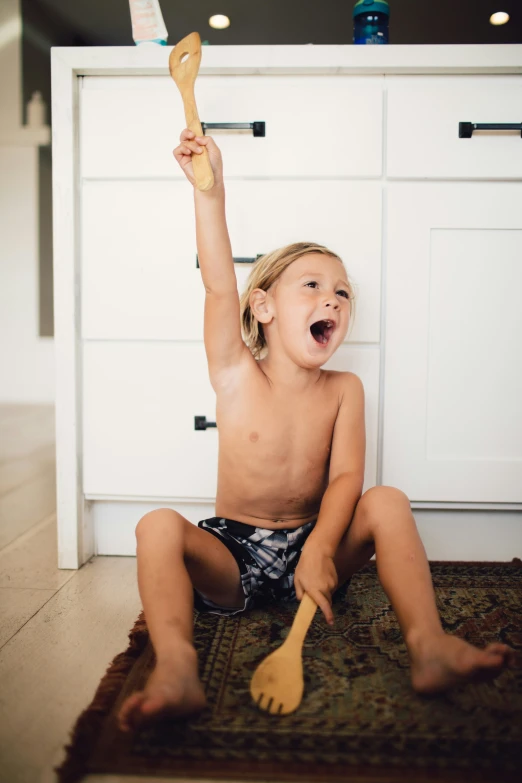 a small child sits on the floor and plays with a brush