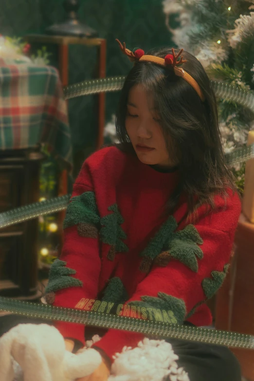 girl sitting down by a christmas tree holding some toys