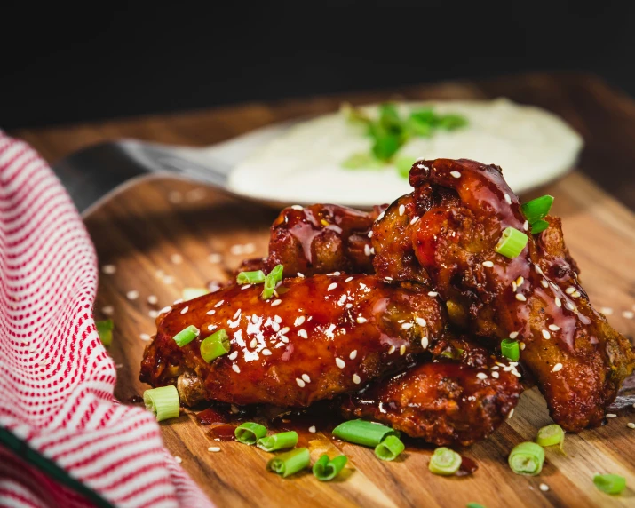 chicken wings and a plate of dressings on a table