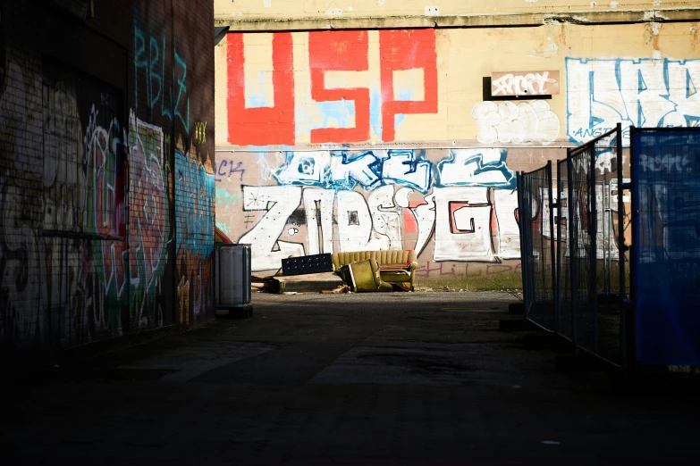 a man sitting in the middle of a long alleyway under a yellow wall