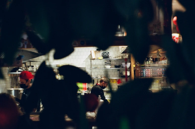 the blurry po shows people standing and working in the kitchen