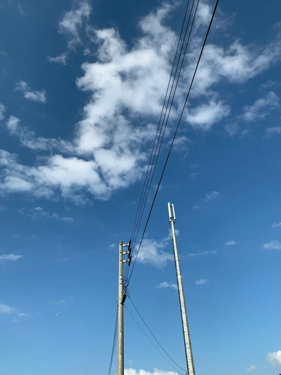 telephone poles and power lines stretching towards a cloud filled sky