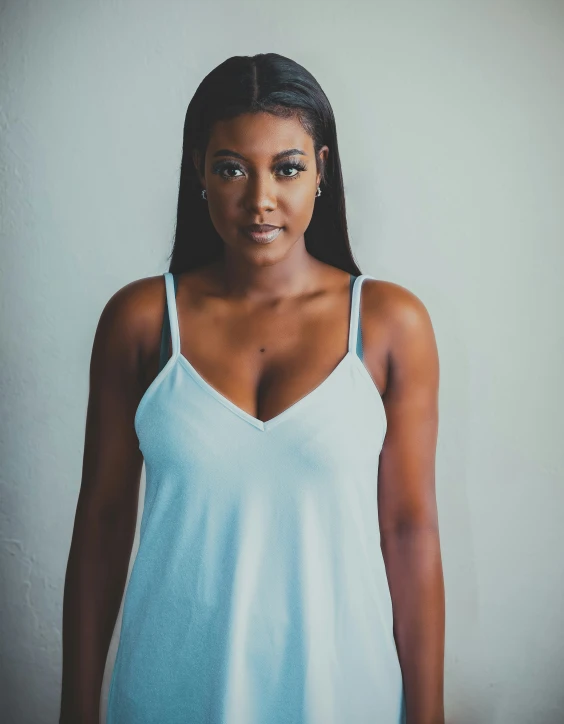 a woman wearing a tank top against a white wall