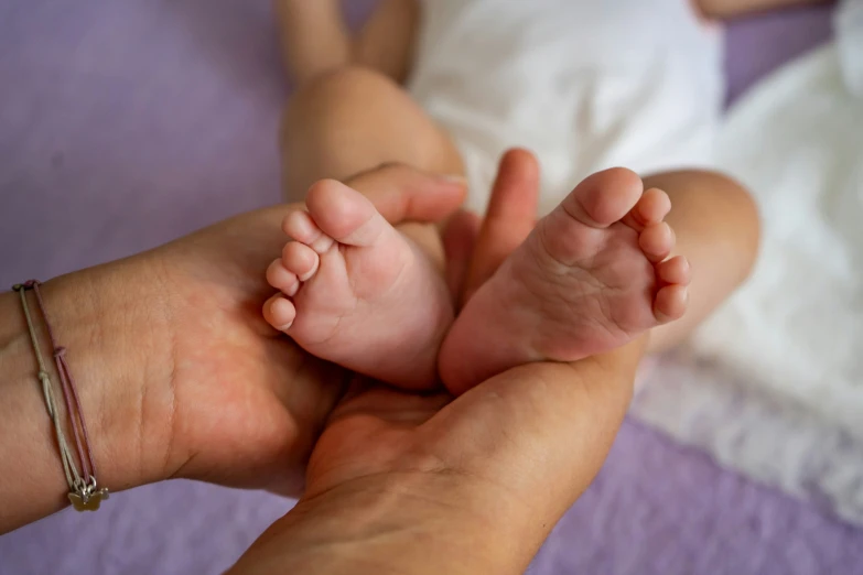 a baby lying on it's back being held in a parent's hands