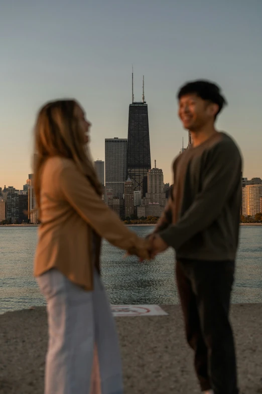 a man and woman holding hands with a city in the background