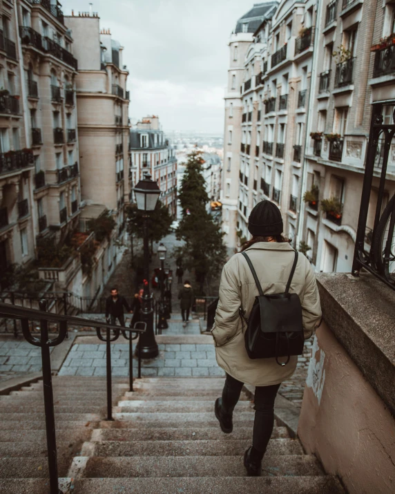 a person in brown coat walking up stairs in city