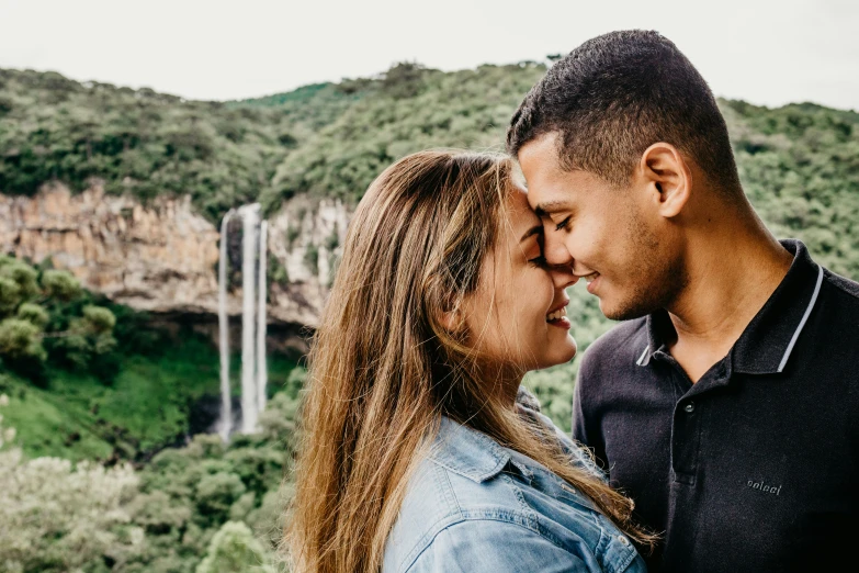 the couple smile as they stand near a waterfall