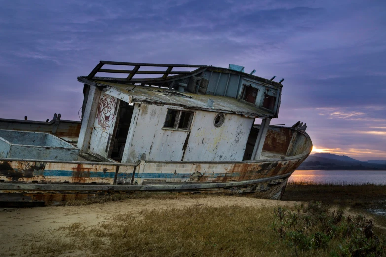 an old ship sitting on top of a field next to a body of water