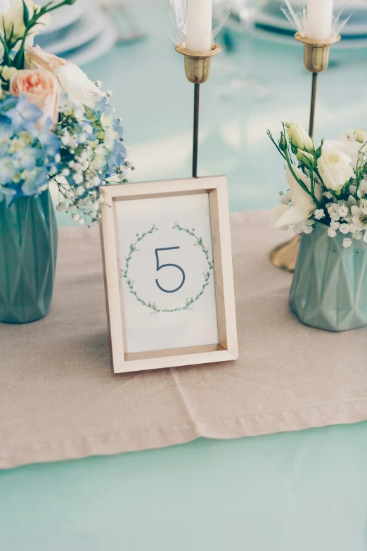 some green vases with white flowers and candles on a table