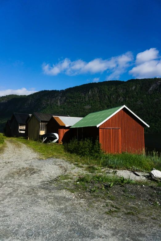 two barns sitting on a farm near a mountain