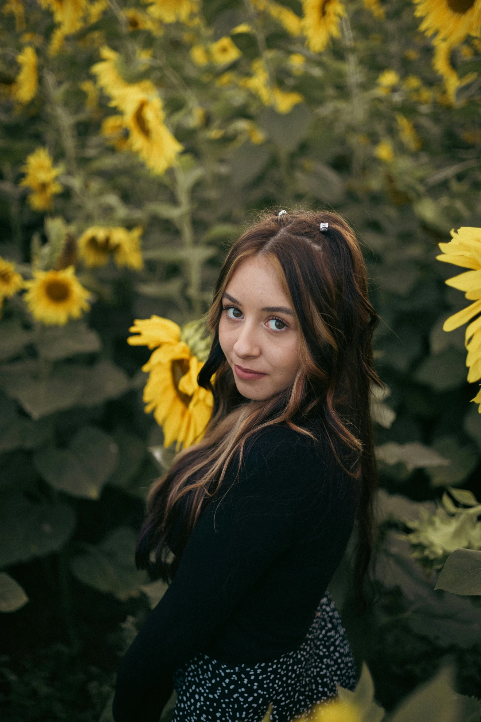 a woman in a field of sunflowers with one eye open