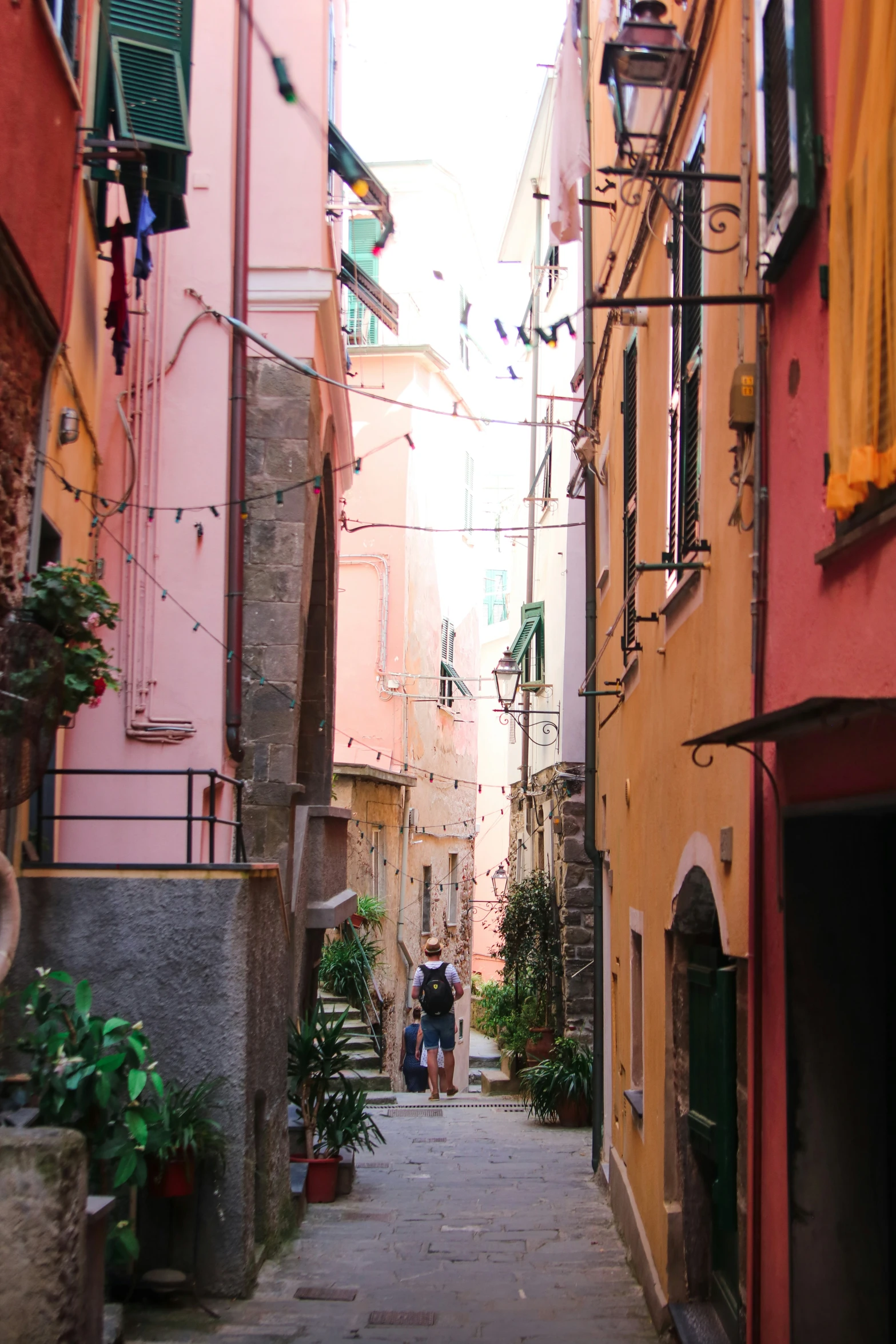 some people walk down an alley way with several buildings