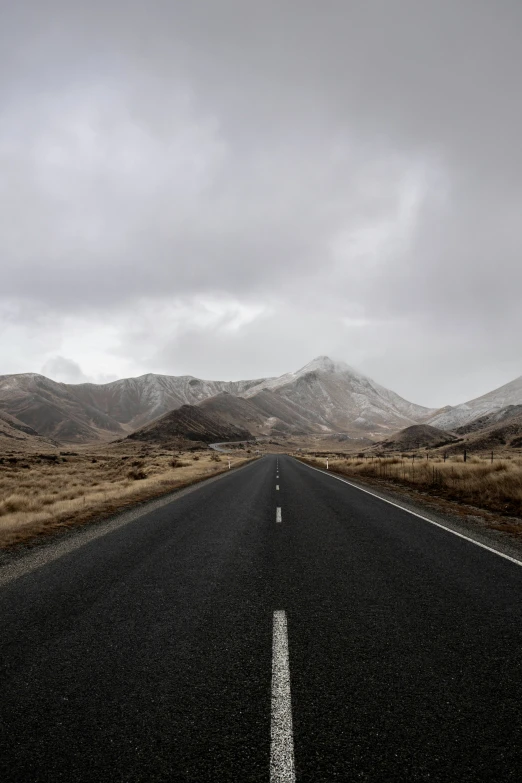 an empty road is shown in the middle of mountains