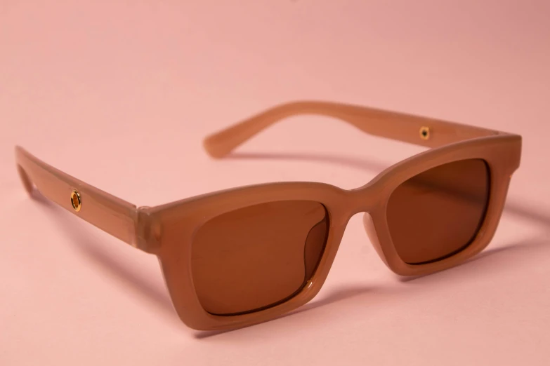 a pair of sunglasses sits on a pink background