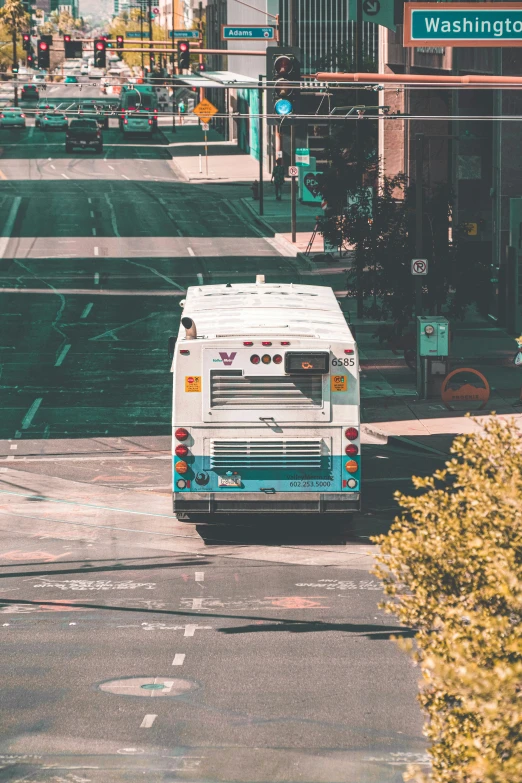 a white bus drives on the street next to buildings