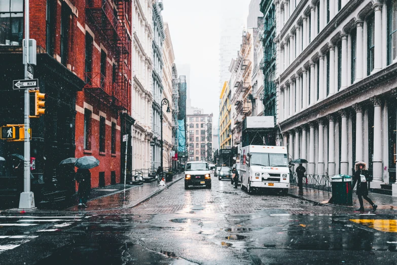 people and traffic on a wet street with a city in the background