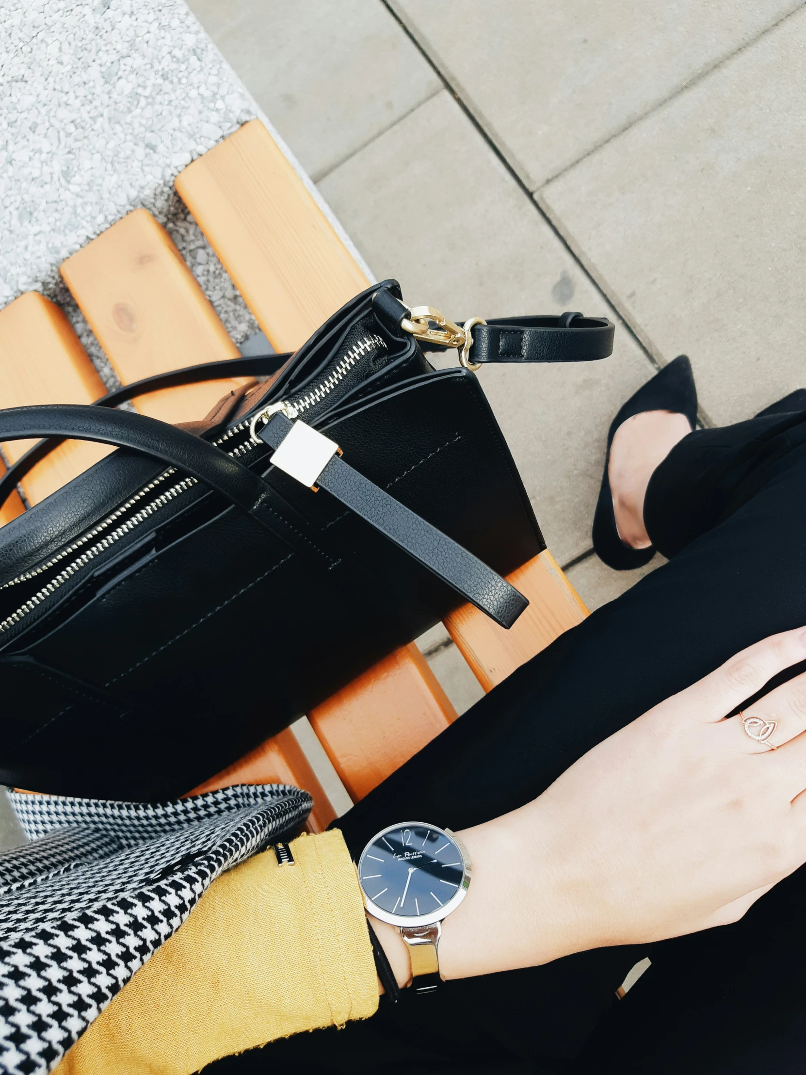 a woman wearing a dress and a watch, sitting on a bench, with her purse