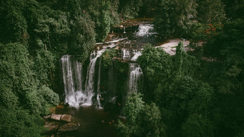 a group of people standing around a waterfall