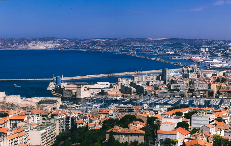 a city with tall buildings sitting in front of a blue sea