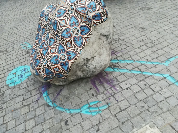 a stone is sitting on the sidewalk near a blue line